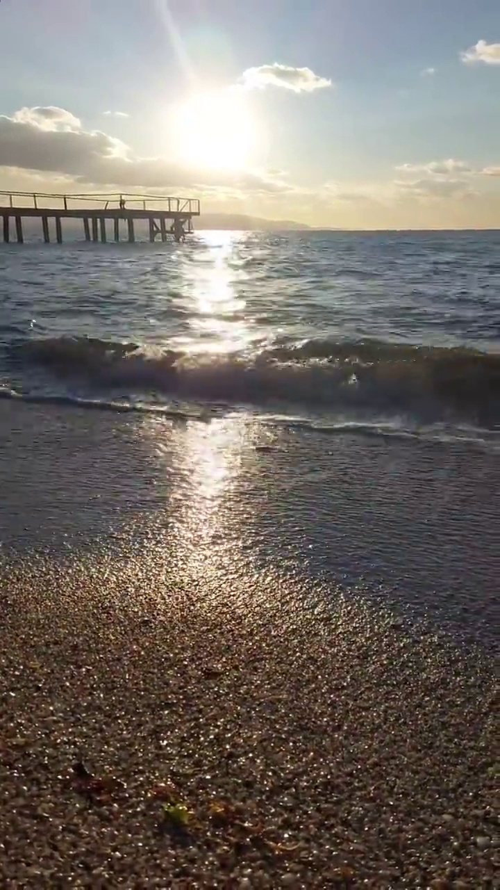 夕阳西下时，海岸上泛起柔和的波浪视频素材