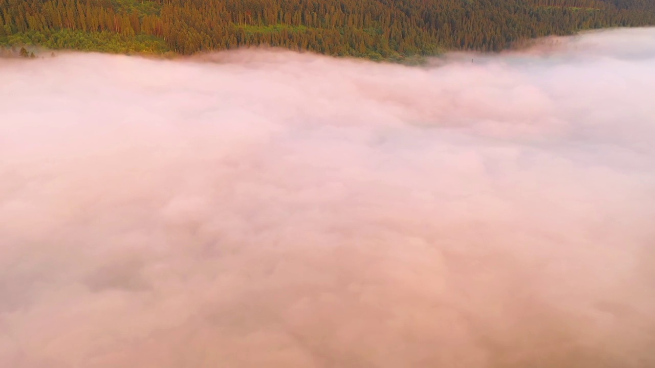 一架无人机在日出时飞过一个风景如画的雾蒙蒙的山谷。视频素材