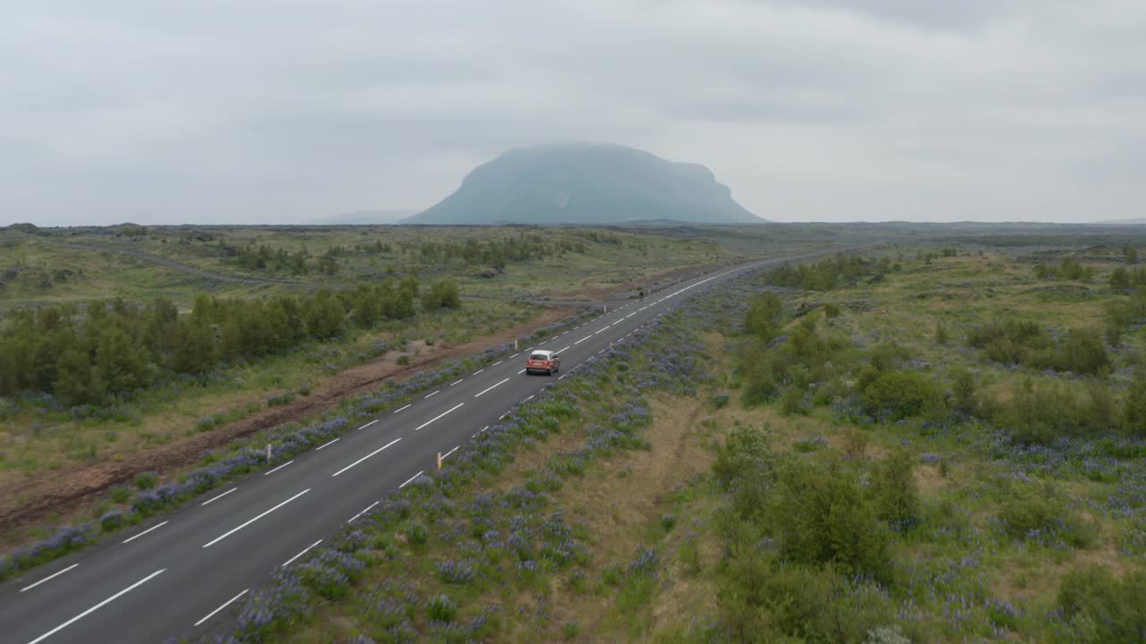 鸟瞰汽车平静地行驶在冰岛最重要的高速公路——环城公路上。鸟瞰图中的汽车沿着笔直的道路穿过长满青草的高地山谷视频素材