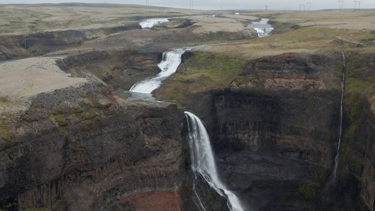 在陡峭的岩壁之上飞行。高瀑布的航拍镜头。北欧的自然美景。Haifoss、冰岛视频素材