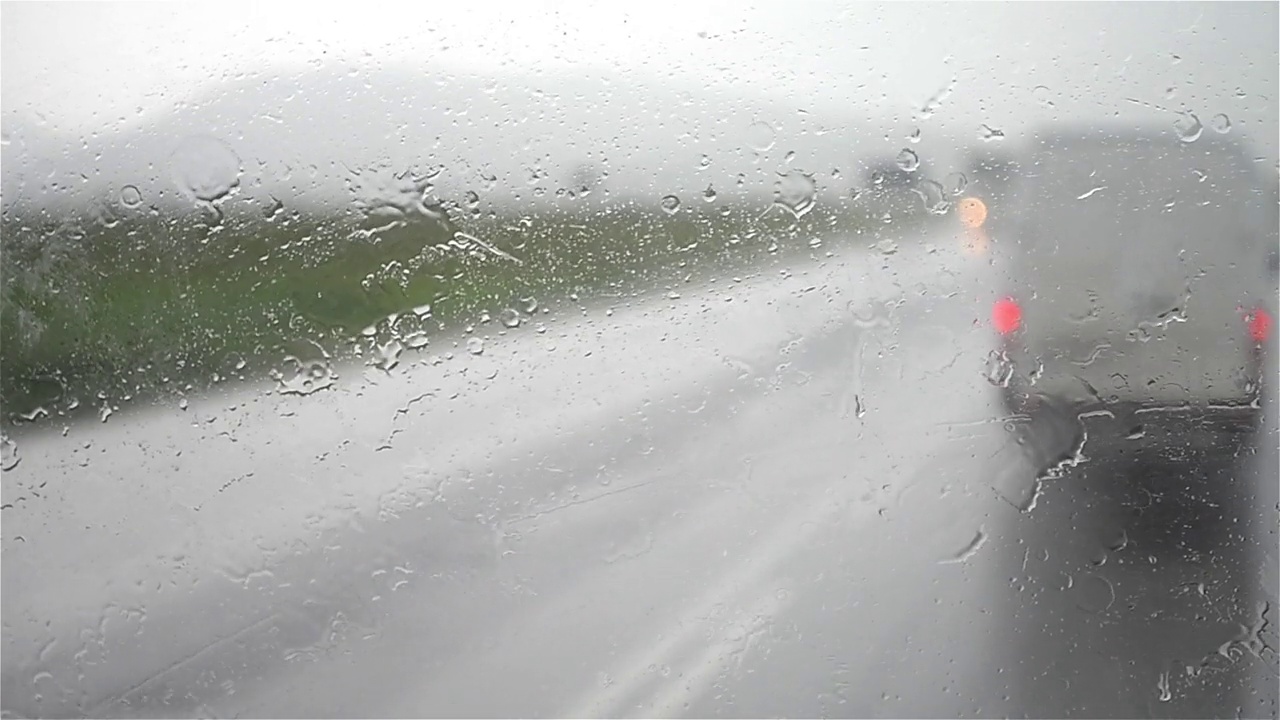 汽车在交通繁忙的道路上高速行驶时，挡风玻璃雨刮器扫水视频素材