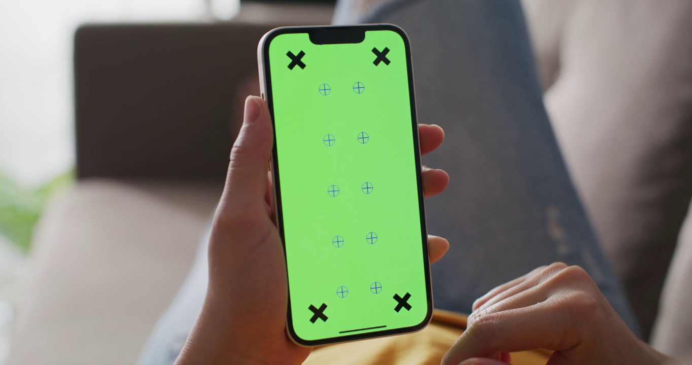 一个认不出来的女人躺在沙发上用一个绿色屏幕的智能手机视频素材