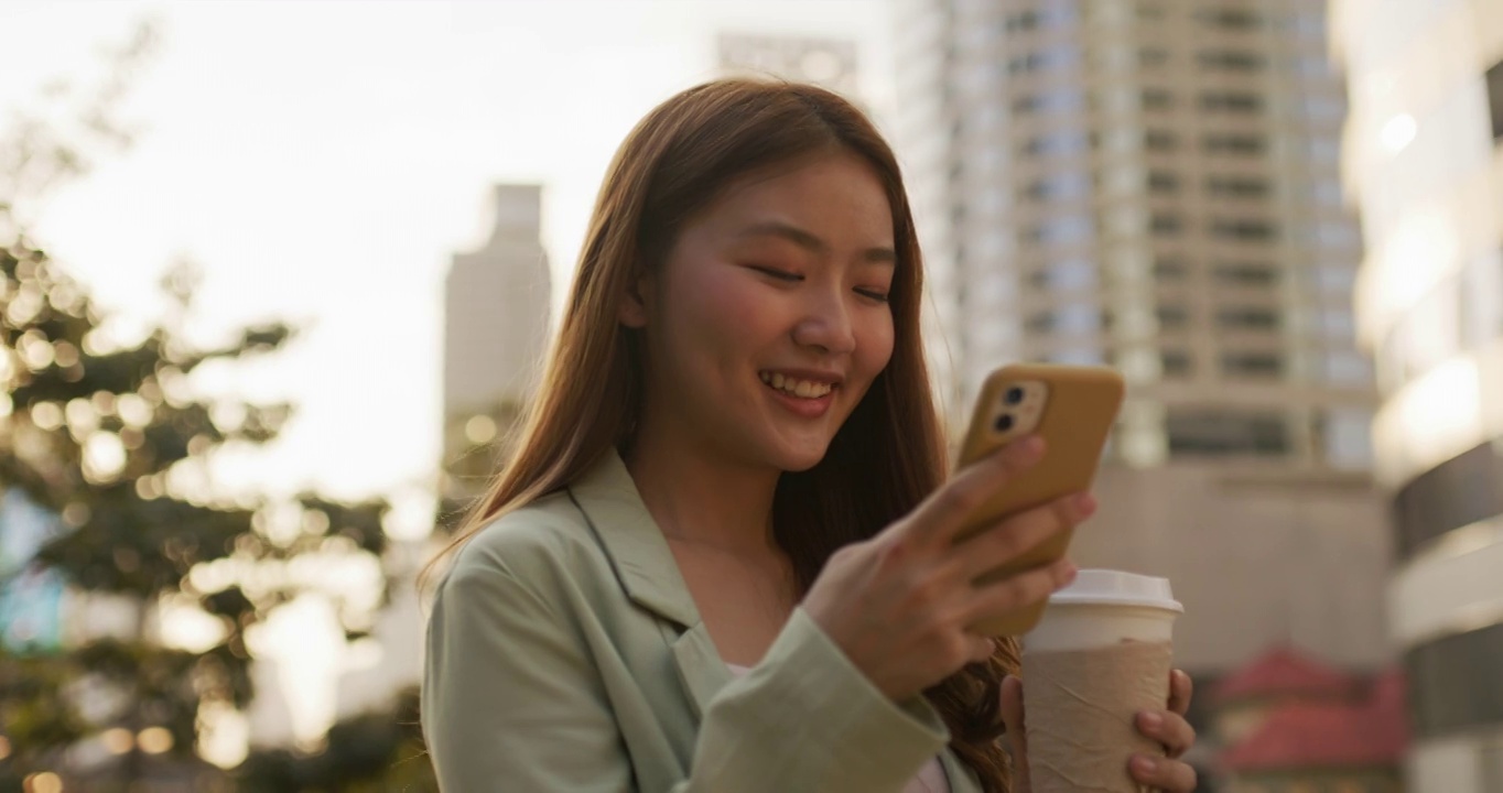 年轻的亚洲女性在城市视野使用手机视频素材