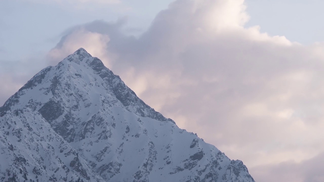 日落在雪山的山峰上，云朵在山峰后面生长视频素材