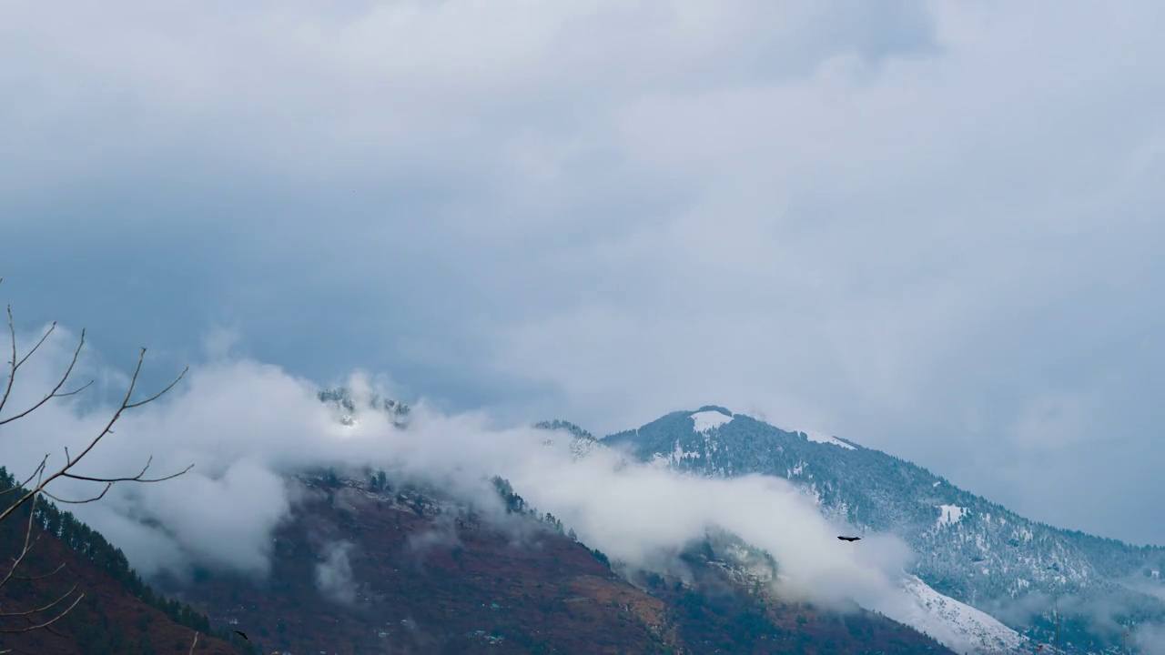 在印度喜马偕尔邦的马纳里，冬季暴风雪期间，积雪覆盖的山脉上空的黑色冬季云的延时拍摄。冬季喜马拉雅山脉的云朵延时。视频素材