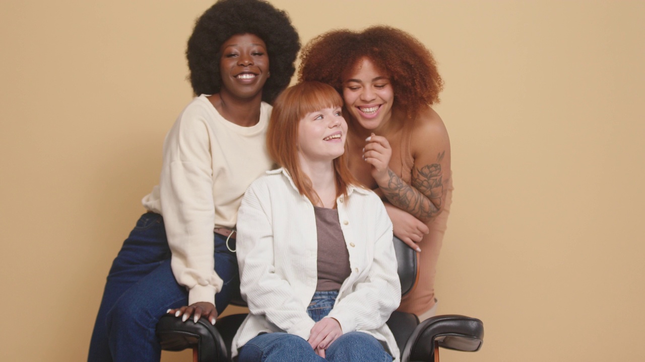 不同种族的女性坐在扶手椅上拥抱并大笑视频素材