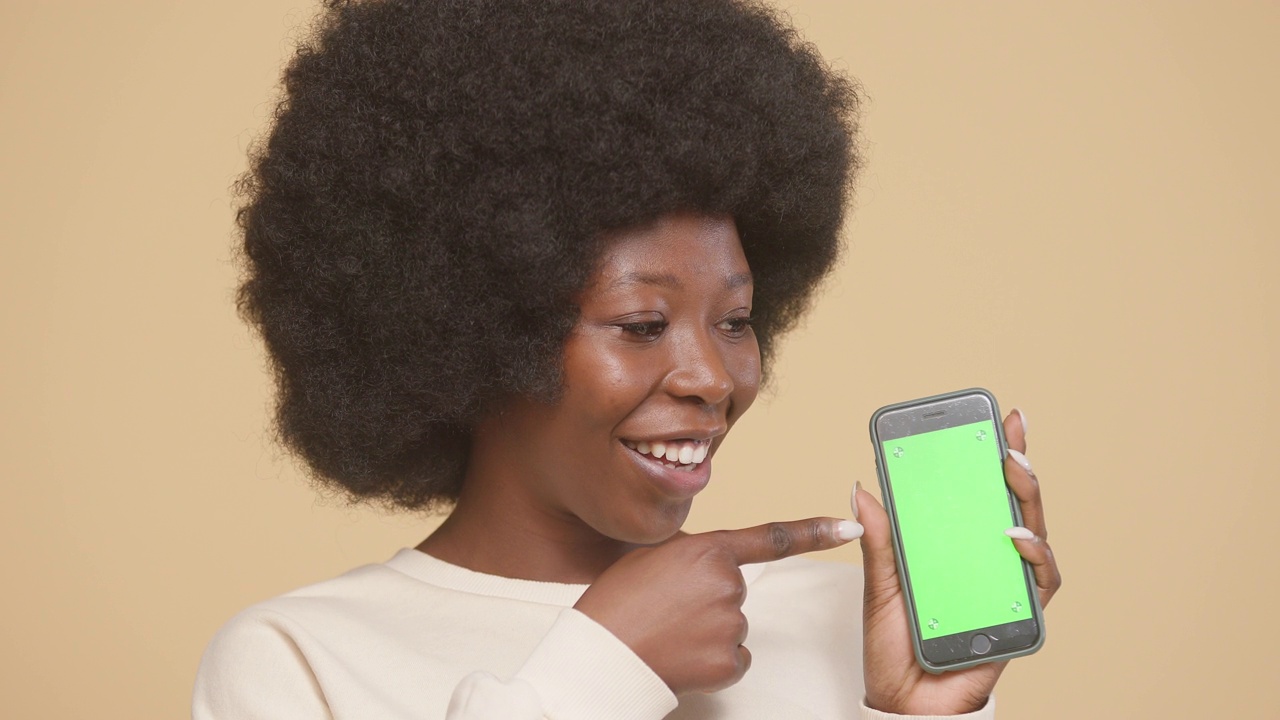 非洲裔美国女性正在展示带有绿色色度键的智能手机视频素材