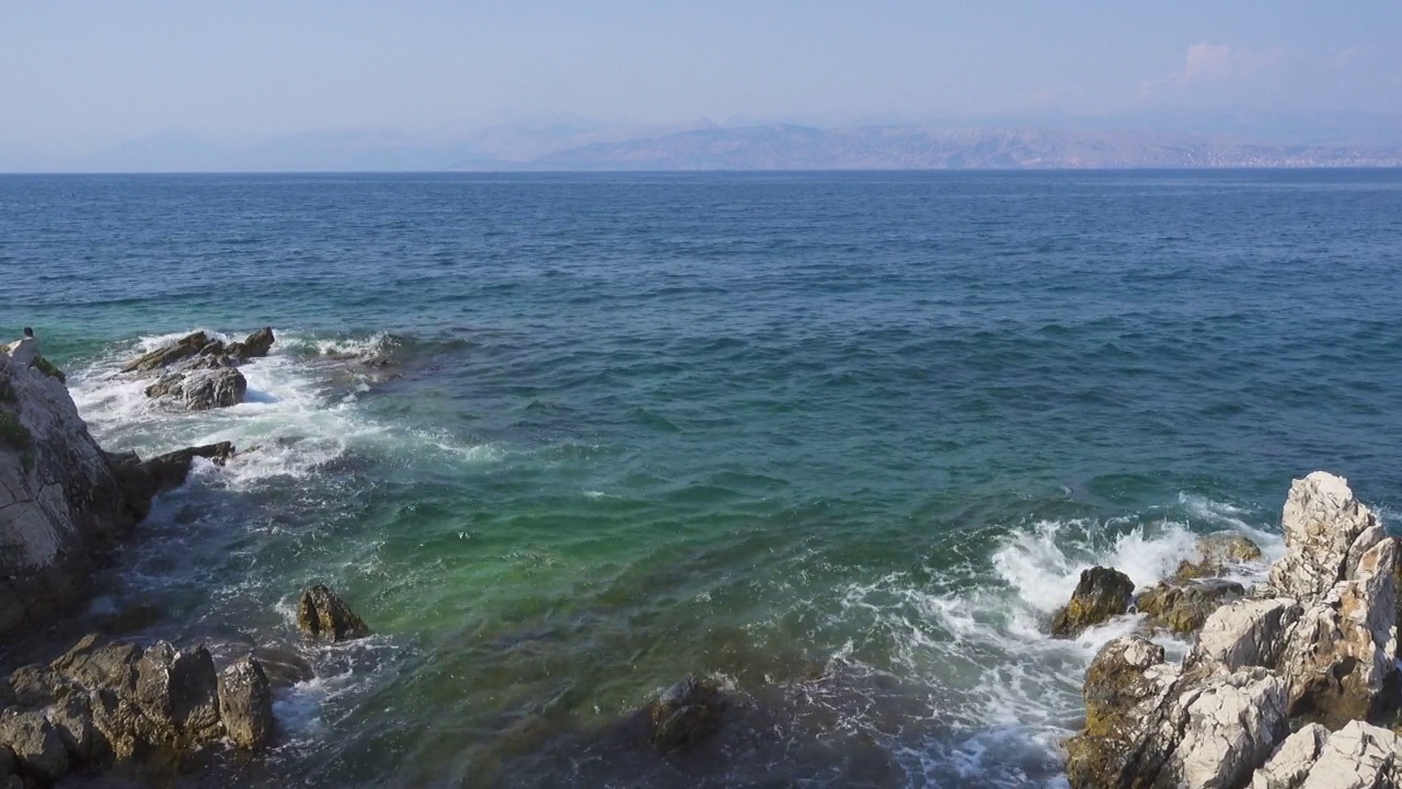 希腊岛屿的岩石海岸，平静的蓝色海面上波涛汹涌视频素材