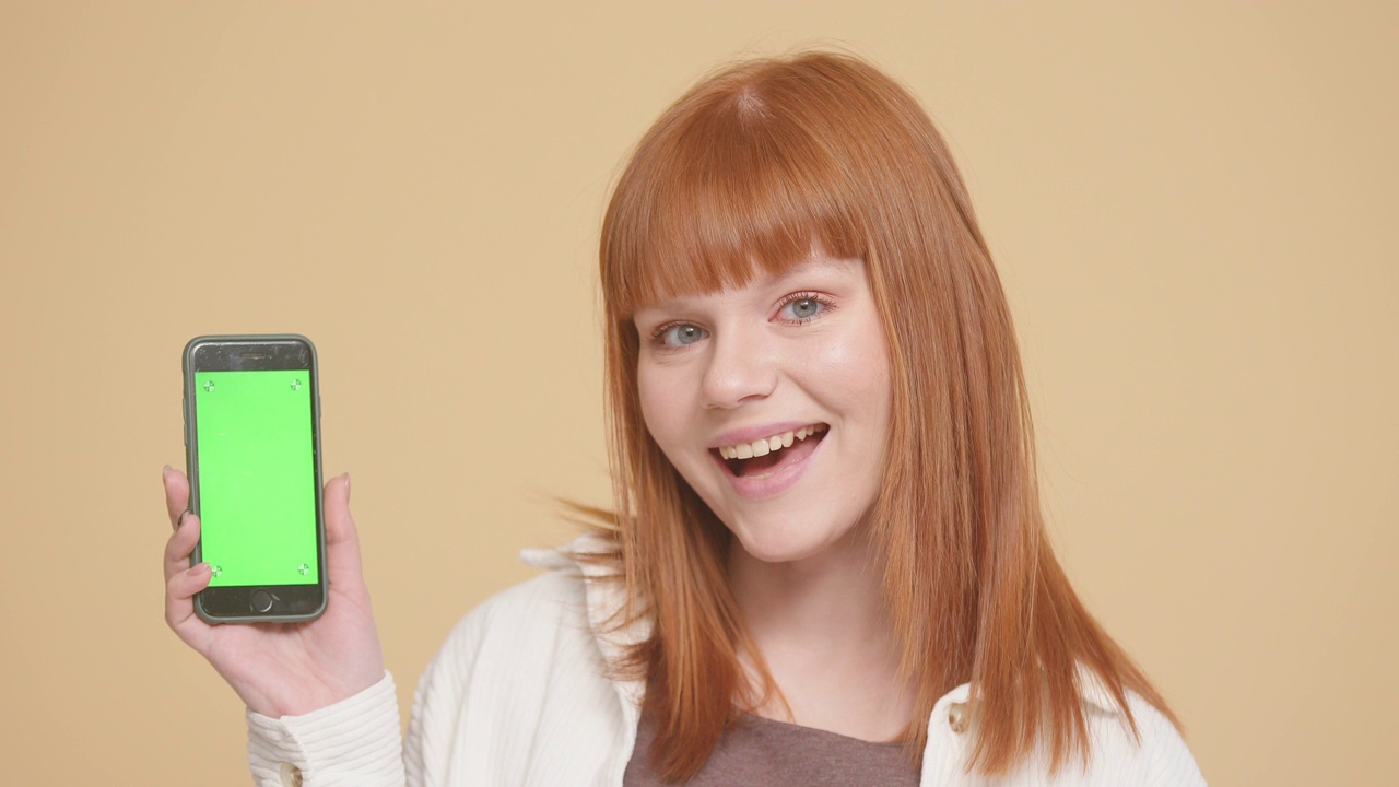 红发白人女性展示智能手机与绿色屏幕的色度键视频素材
