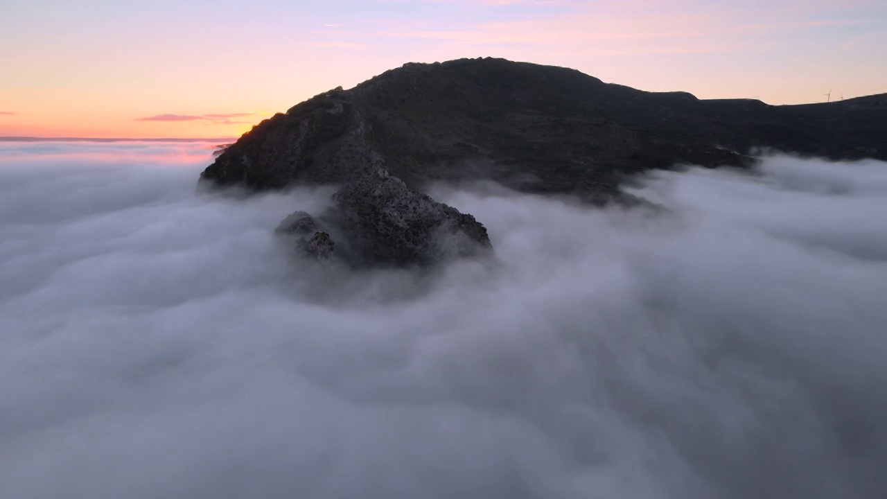 空中拍摄的雄伟的日出景象。群山之间的山谷被雾笼罩着，被冉冉升起的太阳温暖的光线照亮。高质量4k镜头视频素材