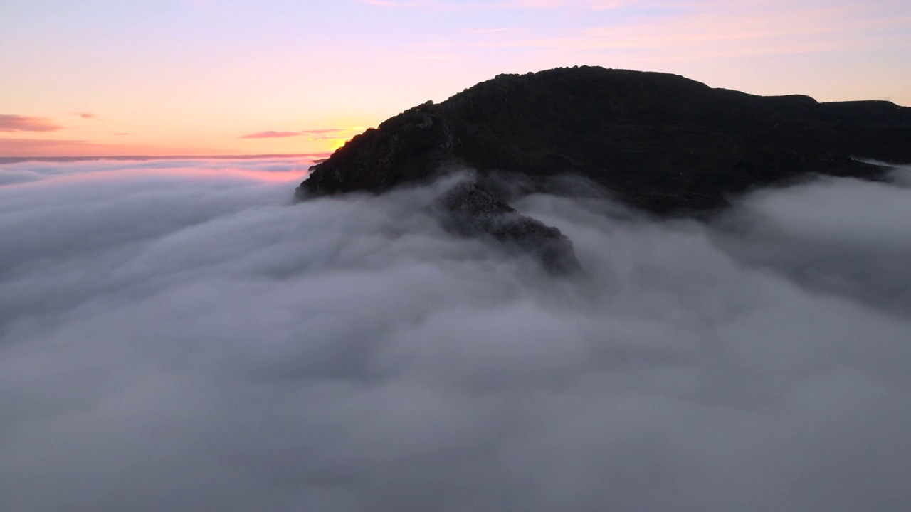 空中拍摄的雄伟的日出景象。群山之间的山谷被雾笼罩着，被冉冉升起的太阳温暖的光线照亮。高质量4k镜头视频素材