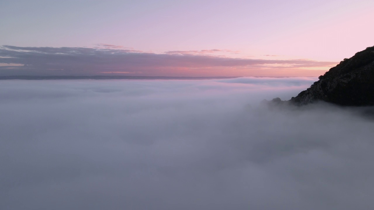 空中拍摄的雄伟的日出景象。群山之间的山谷被雾笼罩着，被冉冉升起的太阳温暖的光线照亮。高质量4k镜头视频素材