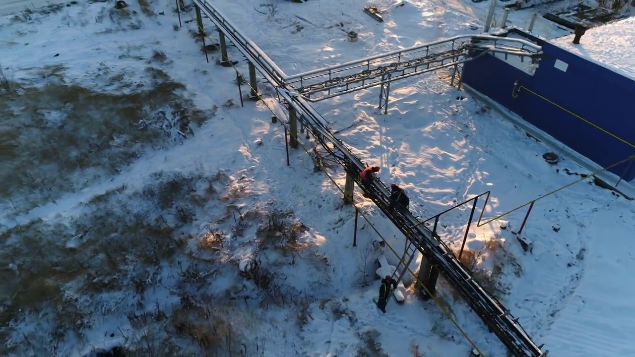 在下雪的院子里，工人在修理车间附近的外管道视频素材