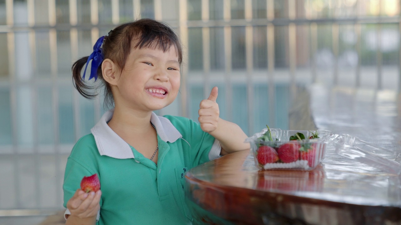 快乐的小女孩在桌子上吃草莓视频素材