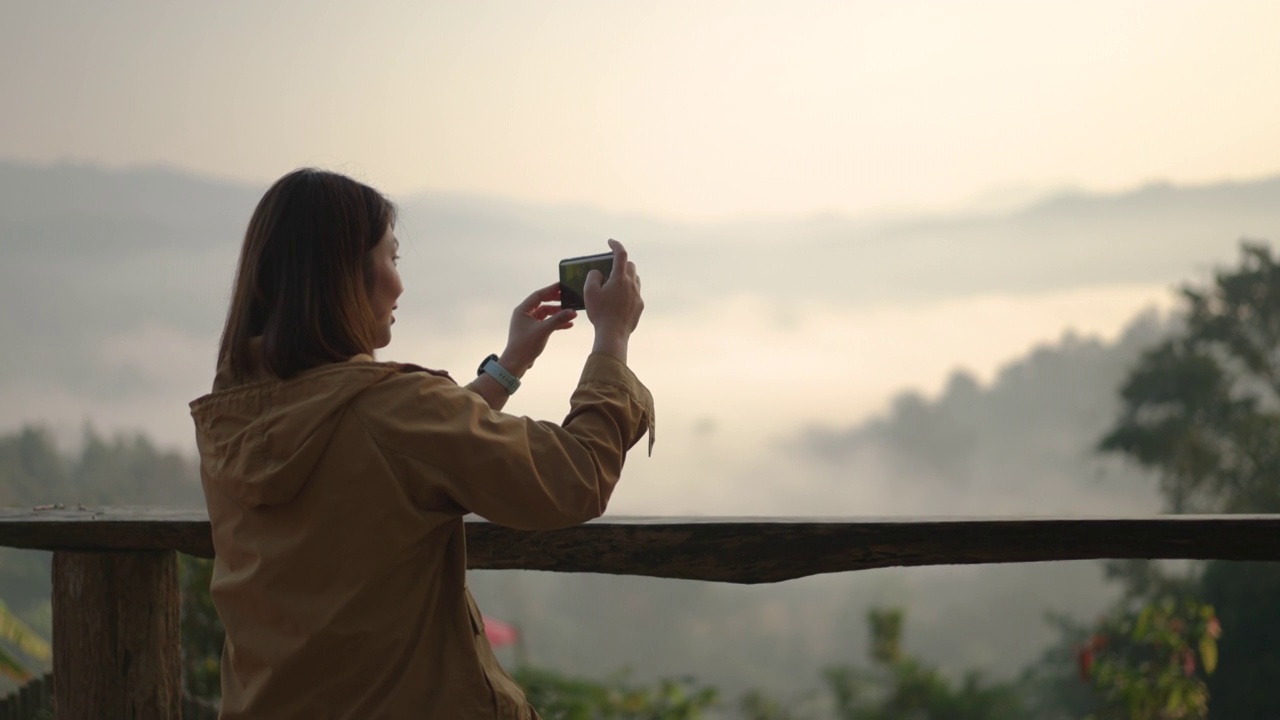 女子在山上放松，用智能手机拍照视频素材