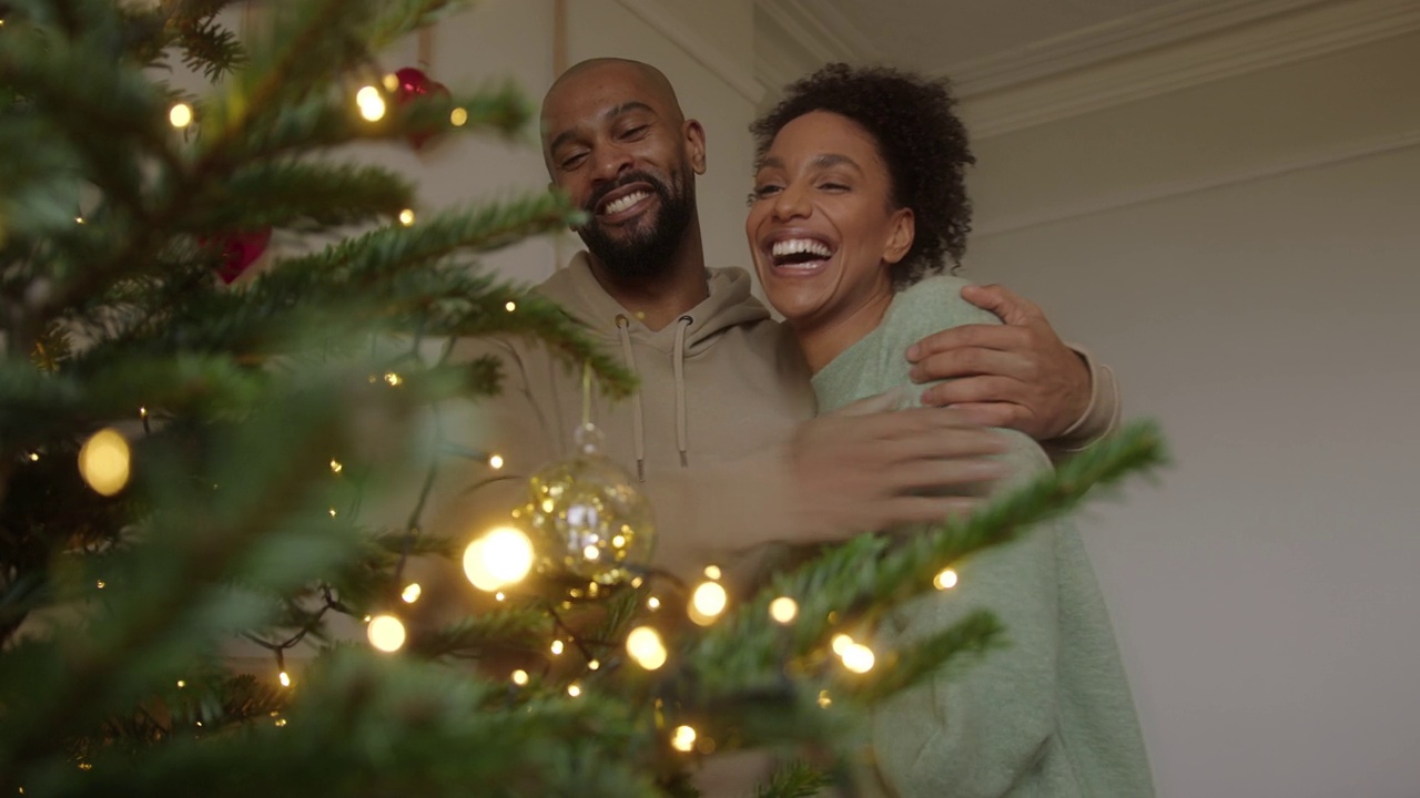 夫妇装饰圣诞树庆祝节日在家里和拥抱视频素材