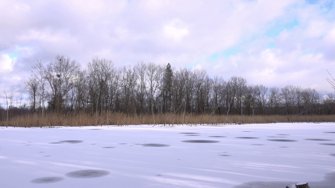 冰雪覆盖的河流和河岸，树木的剪影，冬季景观。视频素材