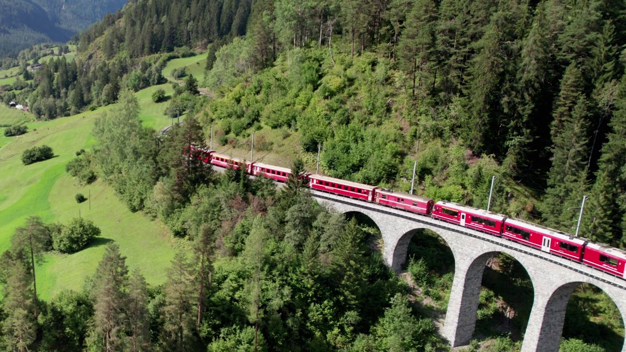 一列红色列车在瑞士阿尔卑斯山的Landwasser高架桥上行驶的鸟瞰图视频素材