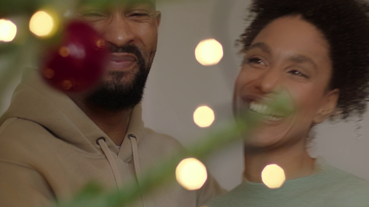 夫妇装饰圣诞树，在家里庆祝节日和拥抱视频素材