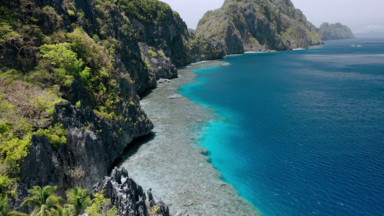 航拍的画面覆盖了游船、岩石山脉和Matinloc神龛附近的珊瑚礁。El Nido，菲律宾巴拉望岛视频素材