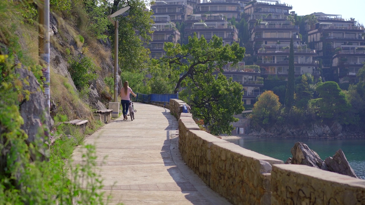 在黑山著名的旅游胜地布德瓦市，一名年轻女子骑着自行车。黑山之旅视频素材