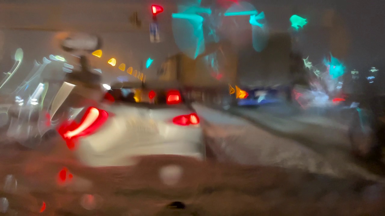 潮湿的道路，特写镜头，汽车行驶在夜晚的冬季街道上。雨雪落在汽车的挡风玻璃上。在恶劣天气，车辆行驶在潮湿、多雨、湿滑的道路上视频下载