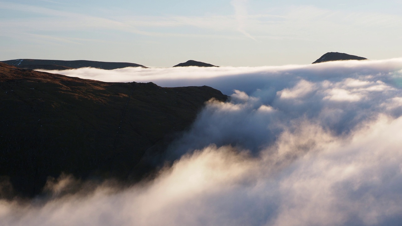 伊尔贝尔和肯特米尔瀑布在黎明时分从英国湖区的红石岭(Red Screes)峰顶的温度逆温下，从山谷的薄雾中探出头来，薄雾在柯克斯通隘口翻滚。视频素材