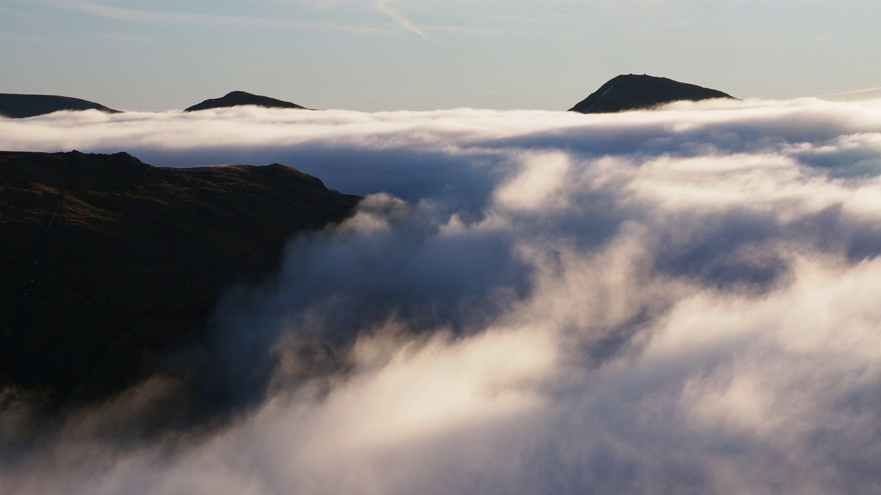 伊尔贝尔和肯特米尔瀑布在黎明时分从英国湖区的红石岭(Red Screes)峰顶的温度逆温下，从山谷的薄雾中探出头来，薄雾在柯克斯通隘口翻滚。视频素材