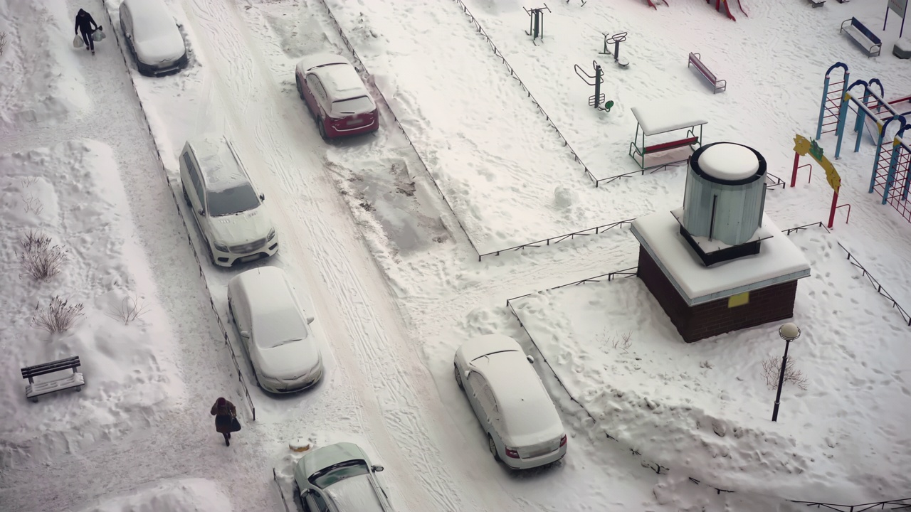 城市的冬天下雪了。停车场的俯视图。路被雪覆盖，车被雪覆盖视频素材