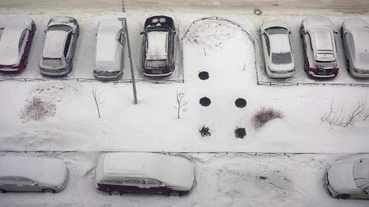 城市的冬天下雪了。停车场的俯视图。路被雪覆盖，车被雪覆盖视频素材