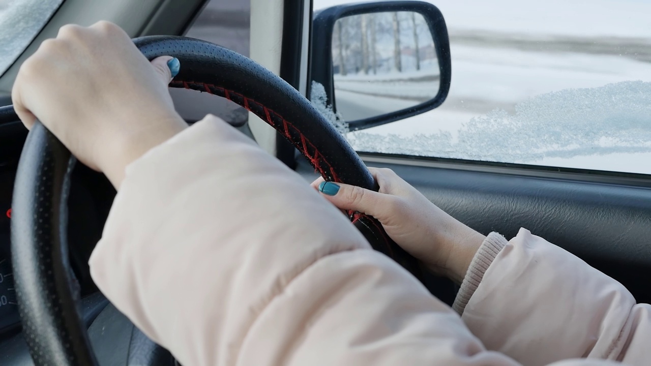 一个女人在冬天的路上开车。绿指甲的手视频素材