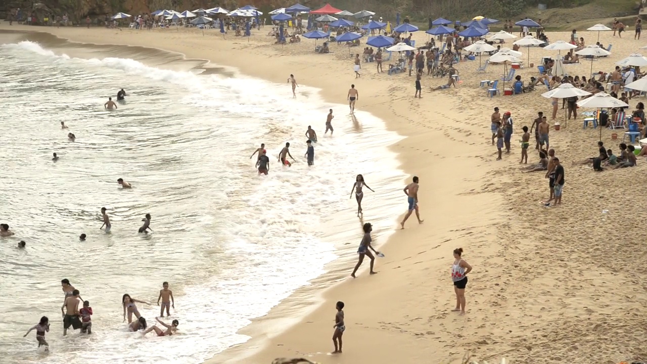 人们在海滩上在海里玩耍和沐浴。视频下载