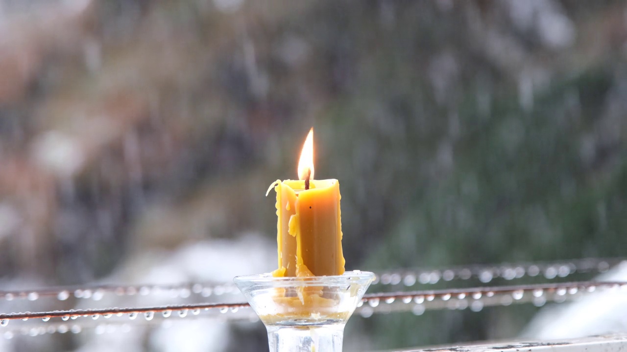 烛光在下雪的背景上。一只小蜡烛在湿漉漉的雪地里燃烧视频素材