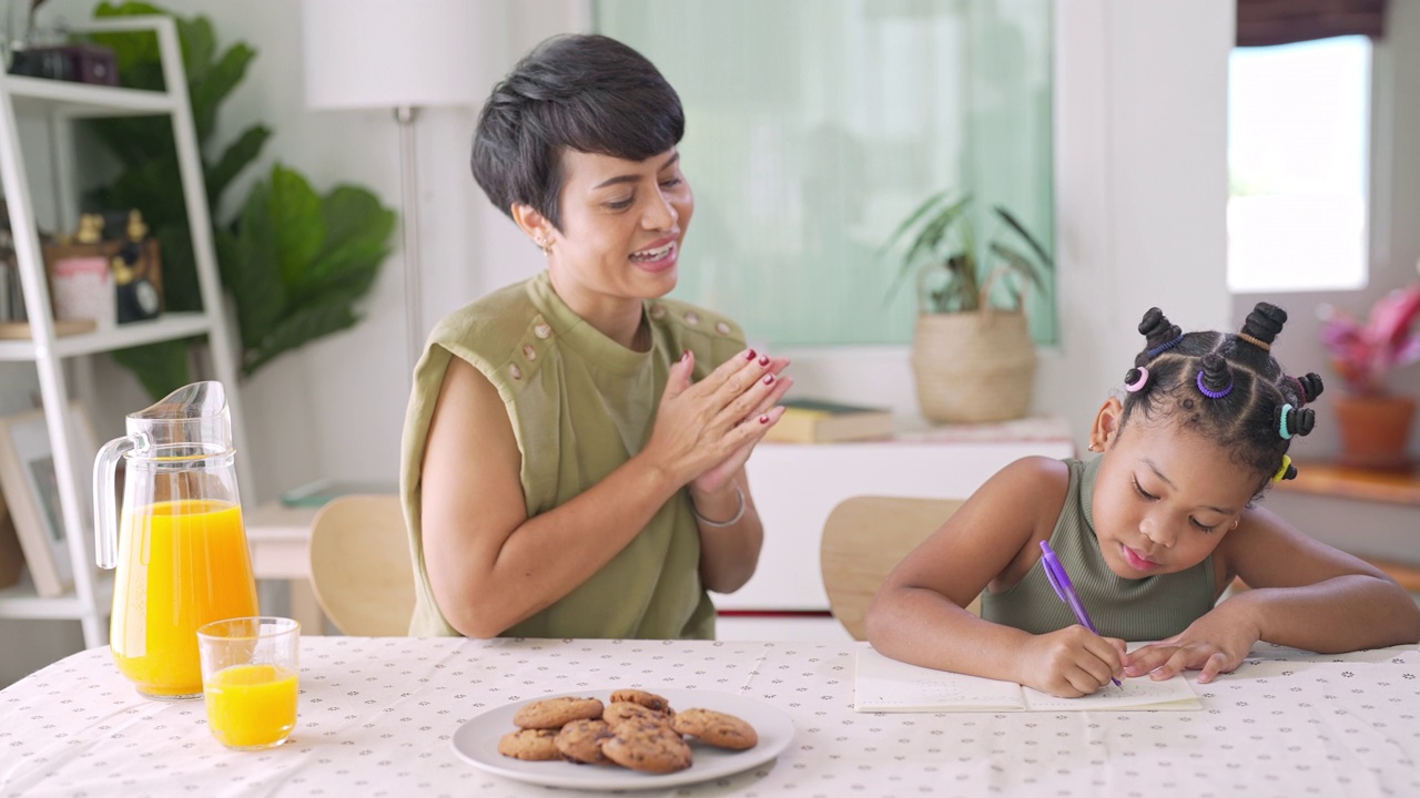 4K妈妈帮小女儿做作业，一起吃饼干视频素材