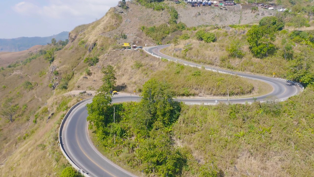 鸟瞰图，汽车行驶在弯曲的，曲折的弯曲的道路或街道上，山上有绿色的天然森林树木，泰国南部的农村地区。交通工具。视频素材