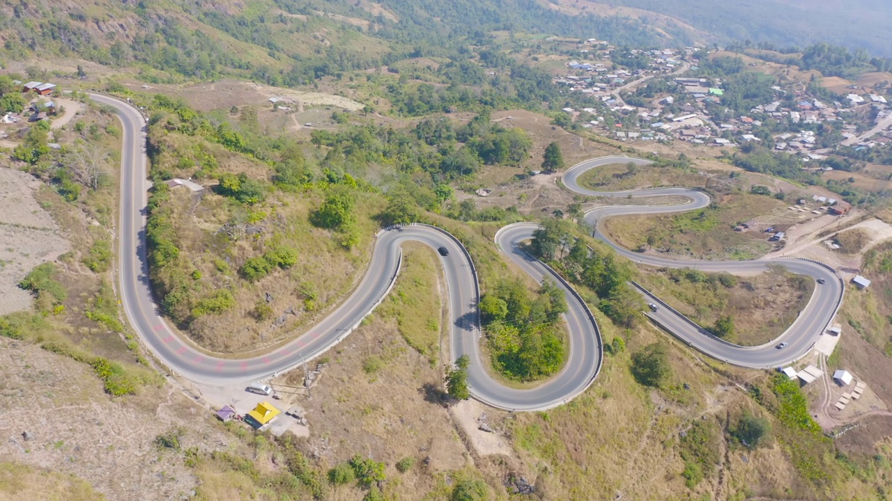 鸟瞰图，汽车行驶在弯曲的，曲折的弯曲的道路或街道上，山上有绿色的天然森林树木，泰国南部的农村地区。交通工具。视频素材