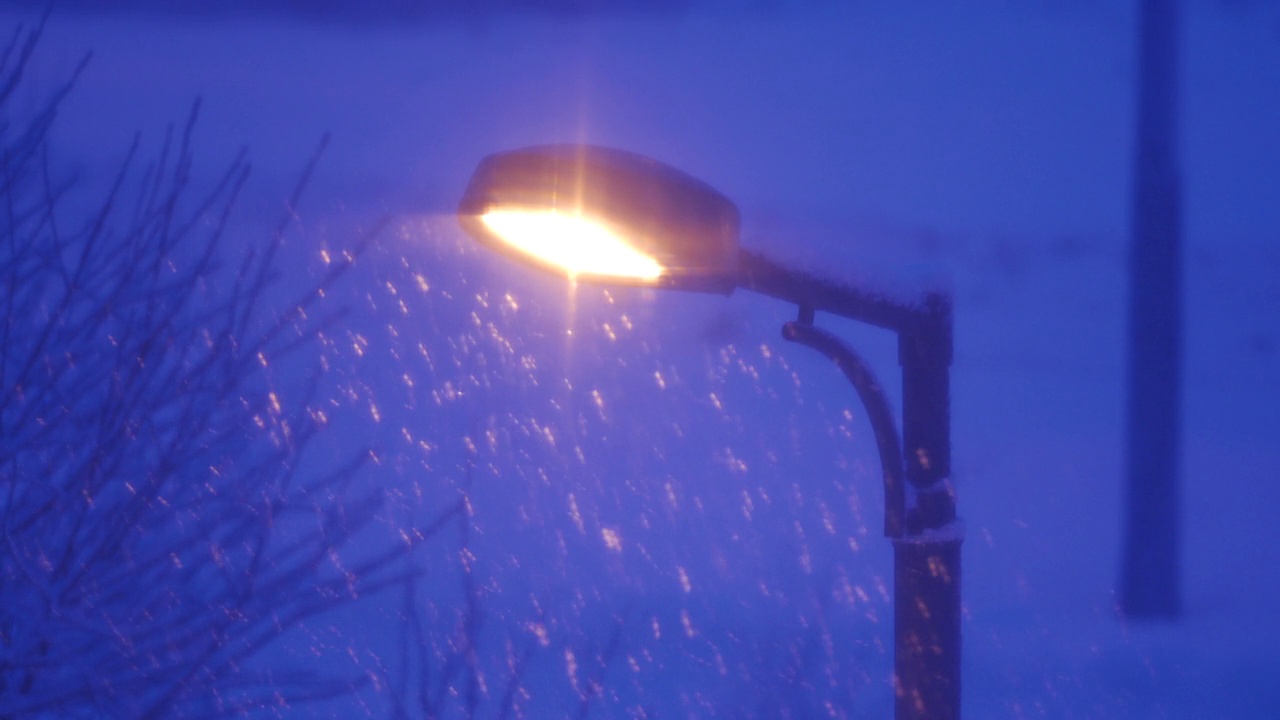 在冬天的夜晚，路灯照亮飘落的雪花。视频素材