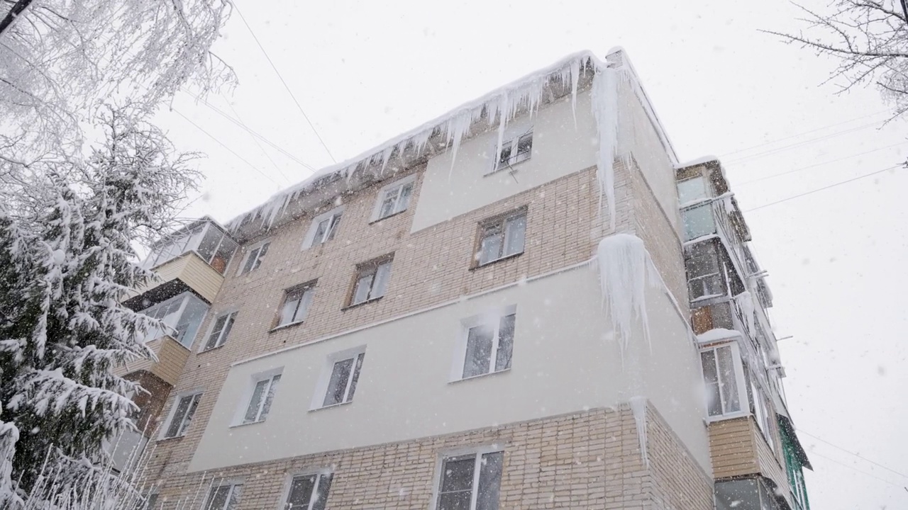 在冬天下雪的时候，俄罗斯赫鲁舍夫卡5层建筑的角落里有巨大的冰柱视频素材