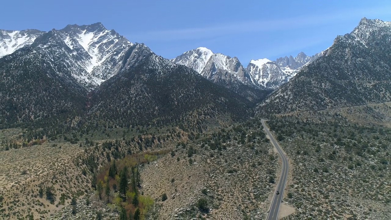 空中美丽的镜头在雪山上的森林，无人机飞行向后在道路-主教，加利福尼亚州视频素材