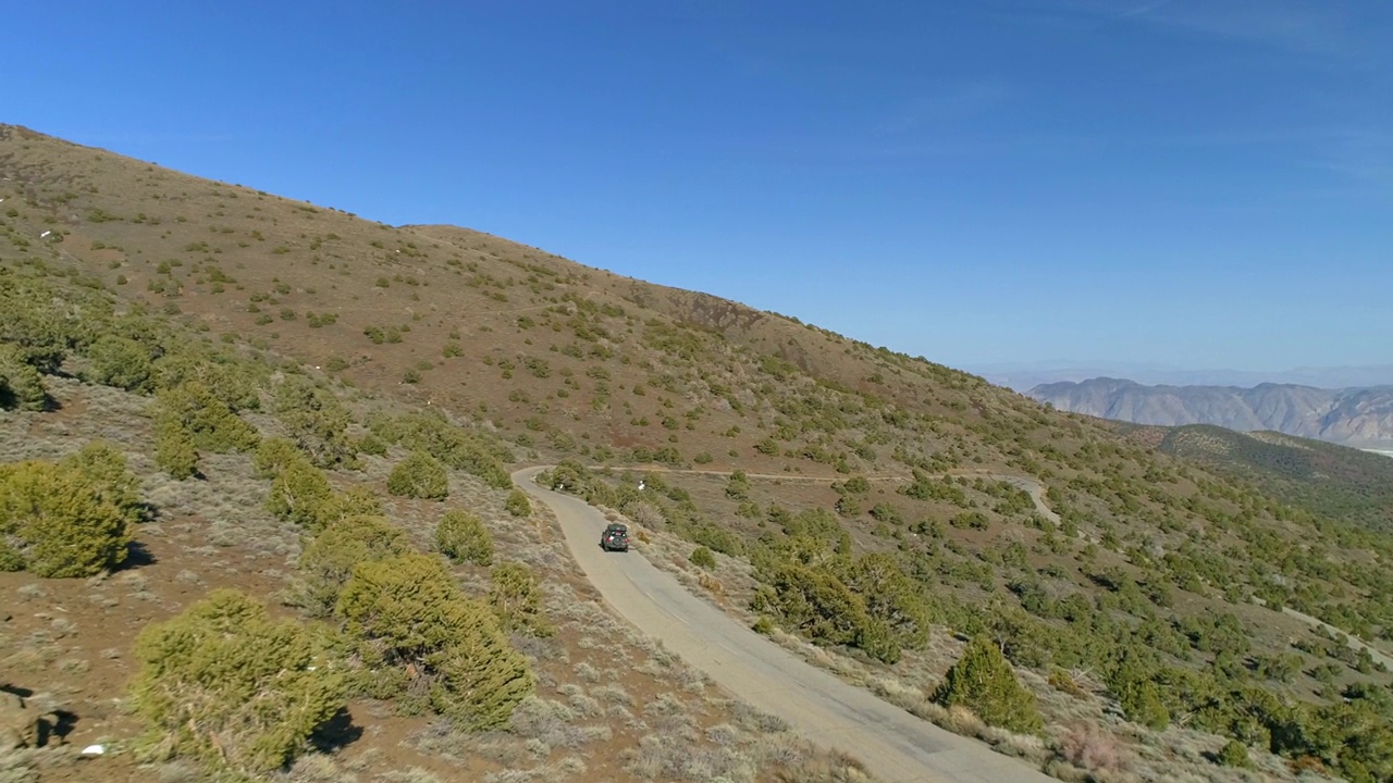 空中向前平移镜头越野汽车在半干旱的景观道路上移动-毕肖普，加利福尼亚视频素材