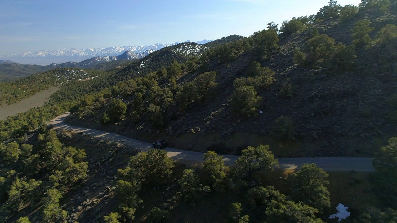 空中风景拍摄的汽车移动在雪山公路，无人机下降在森林-主教，加利福尼亚视频素材