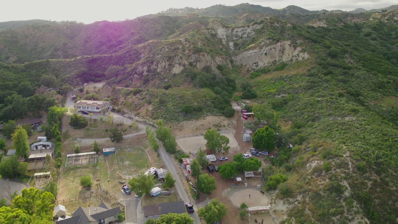 空中向后拍摄的马和人在稳定的地面附近的自然山-圣路易斯奥比斯波，加利福尼亚视频素材