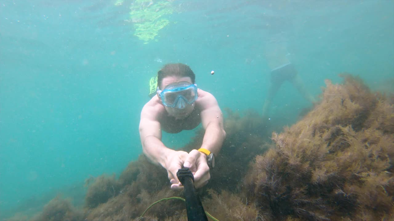 一名白人男子在水下拍摄的自拍照在水下美丽地漂浮着。在海岸或海洋上自由潜水和娱乐的概念视频素材