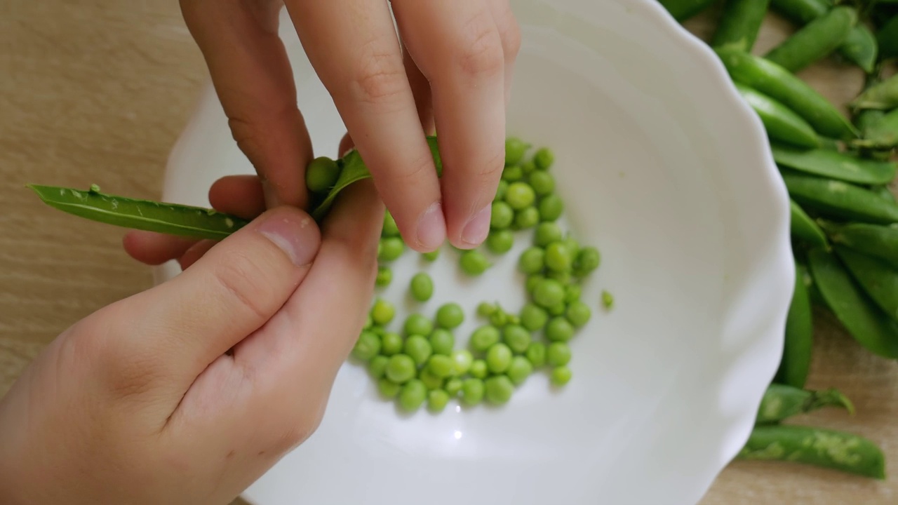 男孩在清理绿豌豆。新鲜蔬菜。从上面的观点视频素材