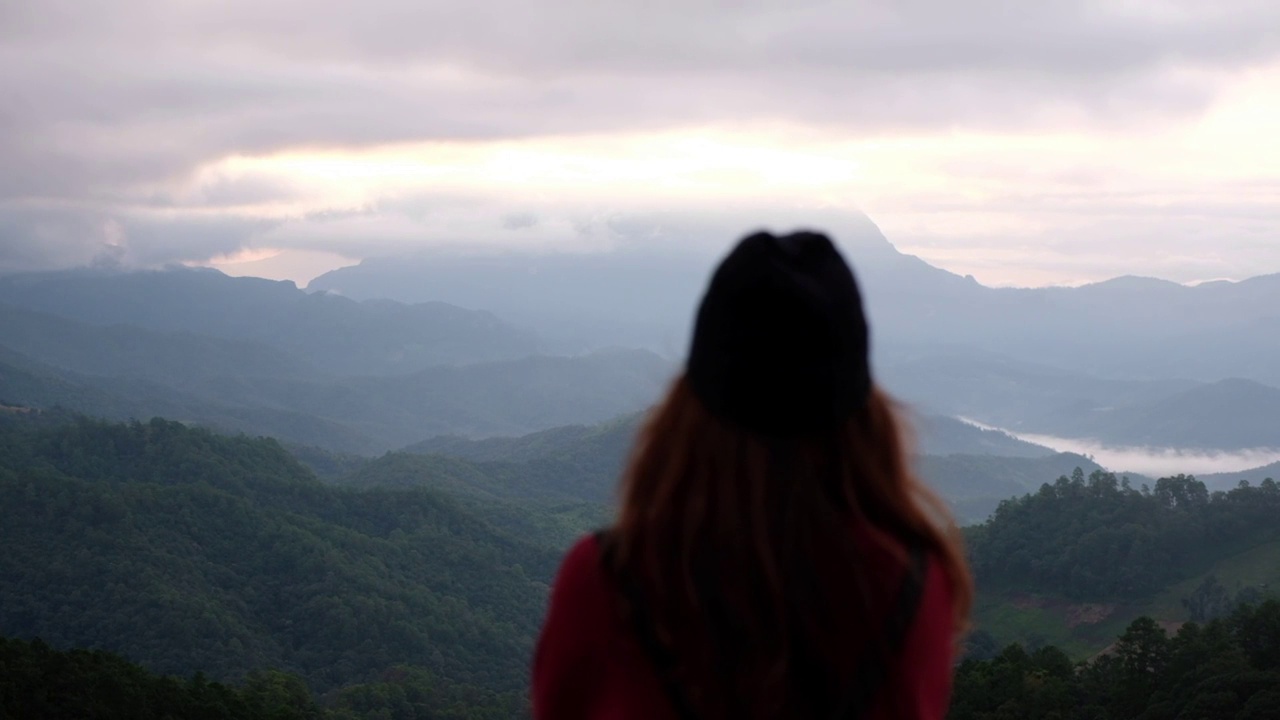 慢镜头模糊的一个女性旅行者看着美丽的山景在雾天视频素材