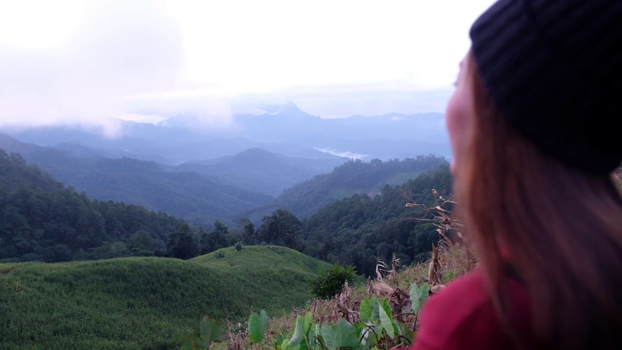 慢动作的一个女性旅行者看着一个美丽的山景在雾天视频素材