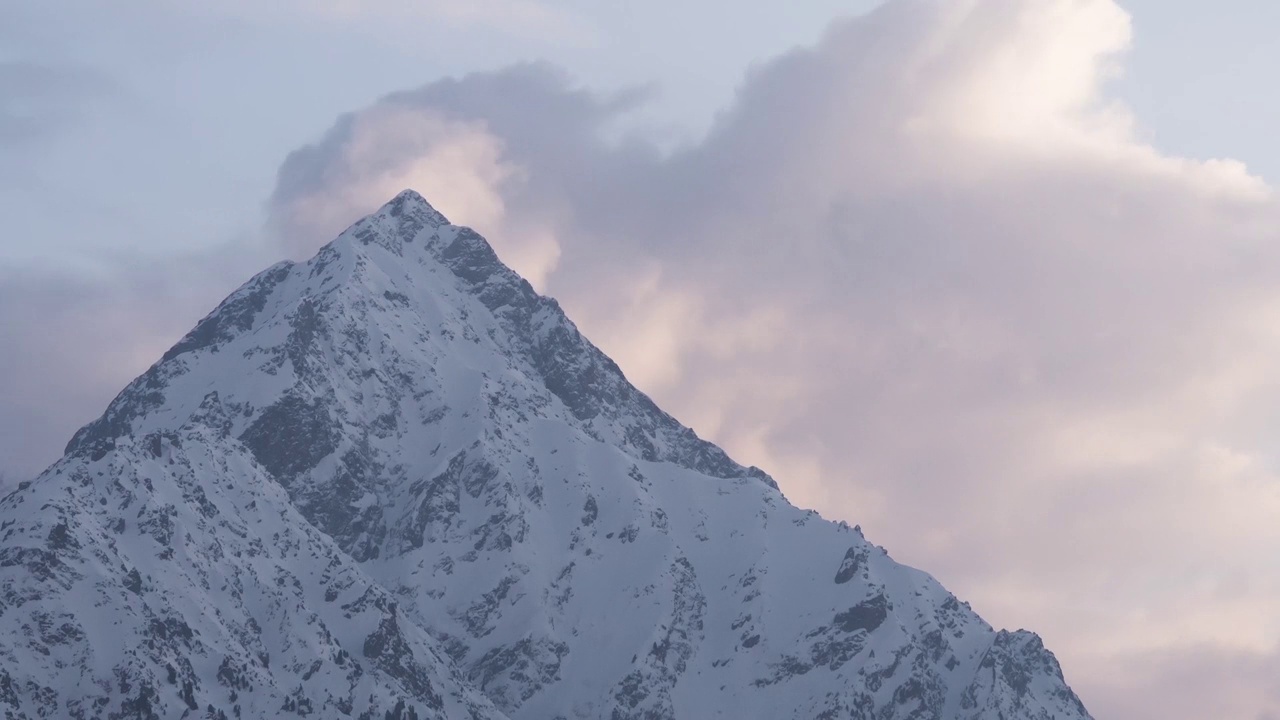 日落在雪山的山峰上，云朵在山峰后面生长视频素材