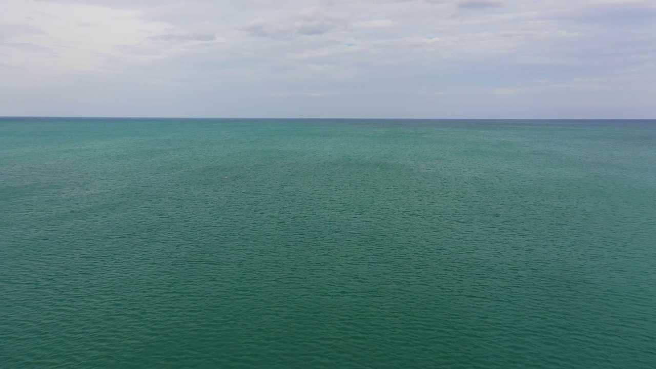 开阔的蓝色海洋，海浪映衬着天空和云层，俯视图视频素材