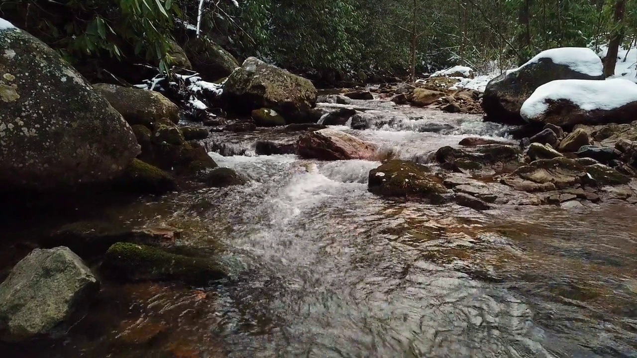 低飞行无人机平移流动的岩石溪在冬季雪视频素材