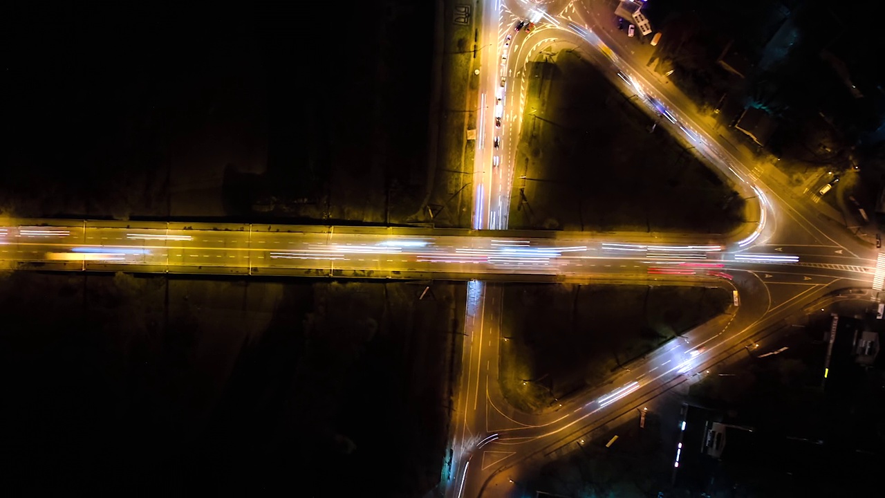 航拍放大在夜间快速移动的交通拥挤的十字路口的视图。城市交通的时间推移。交通高峰期，汽车尾灯模糊不清视频素材